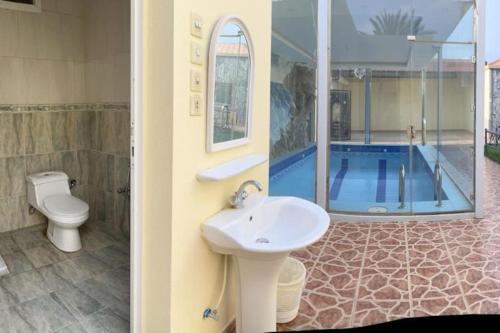 ein Bad mit einem Waschbecken, einem WC und einem Pool in der Unterkunft شالهيات ريست 2 in Ha'il