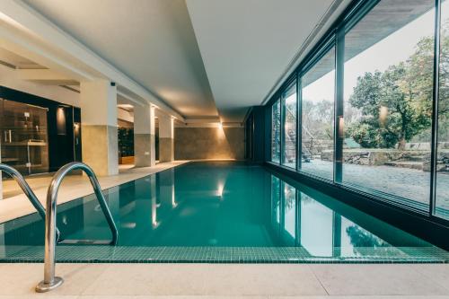 a swimming pool in a building with glass windows at Ribeira Collection Hotel by Piamonte Hotels in Arcos de Valdevez