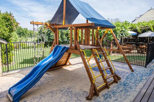 a wooden play set with a slide and a blue slideintend at Peel Inn Hotel Nundle in Nundle
