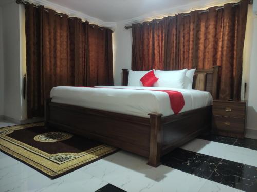 a bedroom with a large bed with red curtains at Bassi Hotel in Takoradi