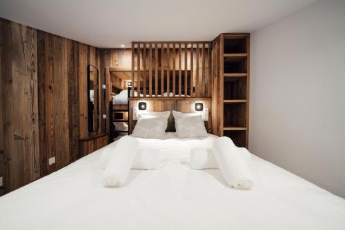 a bedroom with a large white bed with wooden walls at Studio Interlude by ExplorHome in Tignes