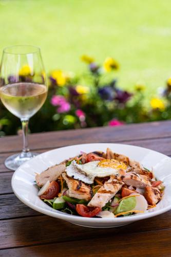 a plate of food on a table with a glass of wine at Peel Inn Hotel Nundle in Nundle