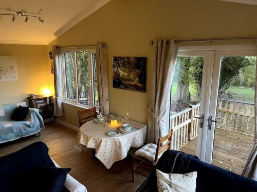 a living room with a table and a balcony at The Lodge at Meadow Hope in Hereford