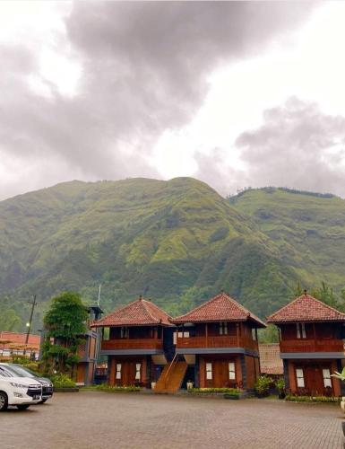 a building with a car parked in front of a mountain at Joglo Kecombrang Bromo in Ngadisari