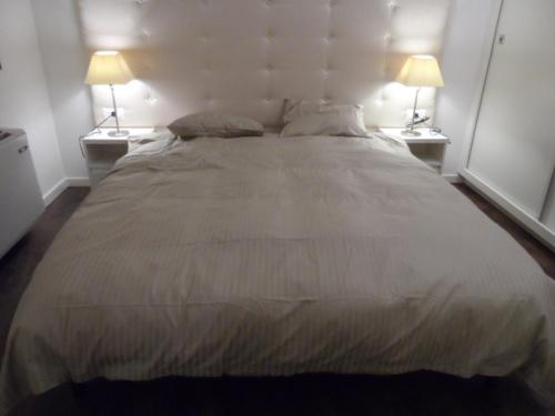 a large bed in a bedroom with two lamps at Erkel Rooftop Suites in Budapest