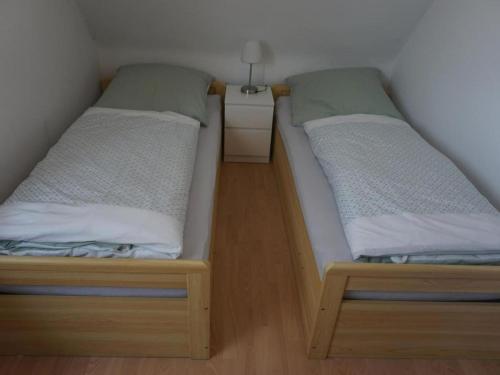 two twin beds in a small room with a night stand at Ferienwohnung Kirsch-Kern in Mössingen