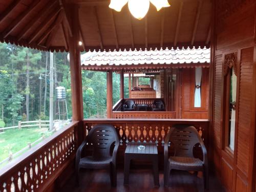 a porch with chairs and a table and a window at Joglo Kecombrang Bromo in Ngadisari