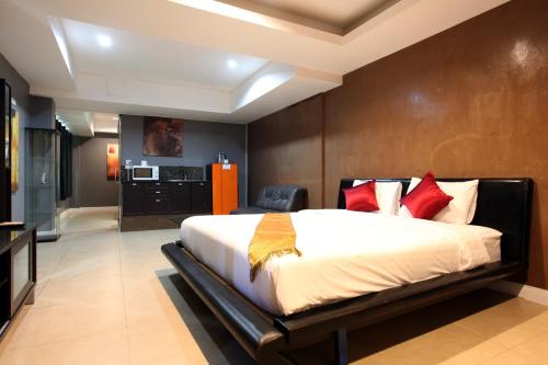 a bedroom with a large bed with red pillows at Del Mar Rooms in Pattaya South