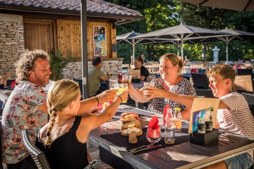 een groep mensen die rond een tafel zitten met drankjes bij Camping RCN La Bastide en Ardèche in Sampzon