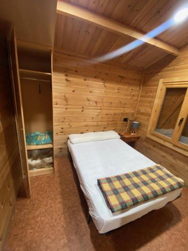 1 dormitorio con 1 cama en una habitación de madera en Bungalow & Camping Fuente De Regrustan en Graus