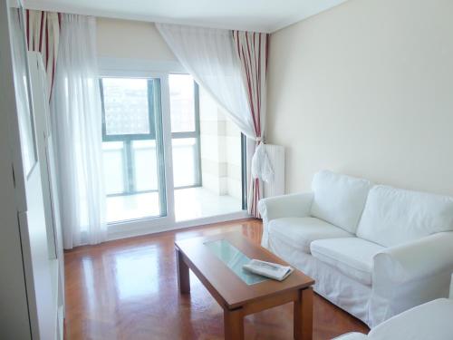 een woonkamer met een witte bank en een salontafel bij Apartamento luminoso, funcional y amplio en zona hospitalaria in Pamplona