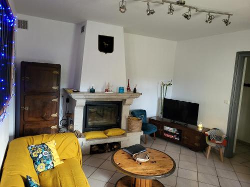 sala de estar con sofá amarillo y chimenea en Maison chaleureuse avec exterieur près de la ville, en Lafox