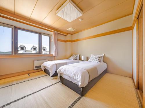 a bedroom with two beds and a window at Red Fox Lodge Myoko in Myoko