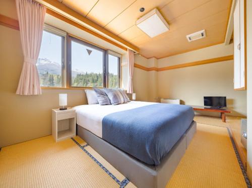 a bedroom with a large bed in a room with a window at Red Fox Lodge Myoko in Myoko