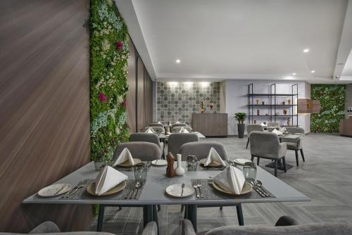 a dining room with tables and chairs and plants at Hotel Holiday International in Sharjah