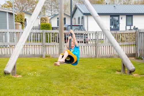 a young child is playing on a swing at Strandcamping Valkenisse in Biggekerke