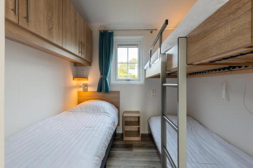 BiggekerkeにあるStrandcamping Valkenisseの二段ベッド2台、窓が備わる小さな客室です。