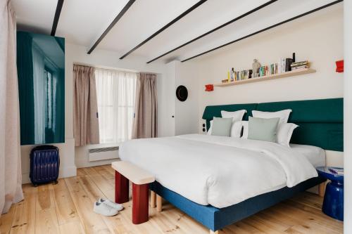 - une chambre avec un grand lit blanc et des touches de vert dans l'établissement Edgar Suites Marais - Nazareth, à Paris