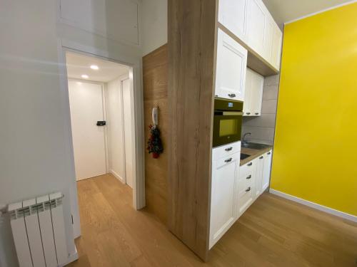 uma cozinha com armários brancos e uma parede amarela em Sendy Home Roccaraso 3 em Roccaraso