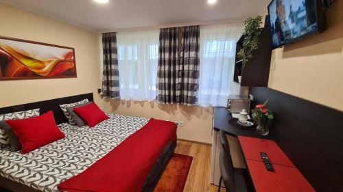 1 dormitorio con 1 cama con almohadas rojas y TV en Lucsony Apartman en Mosonmagyaróvár
