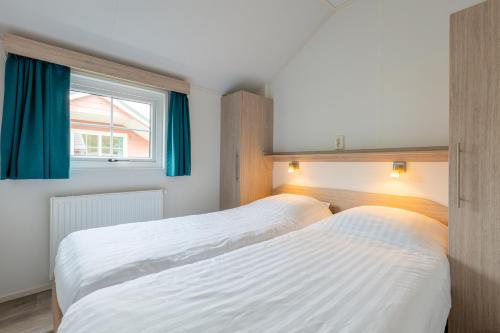 two beds in a room with a window at Strandcamping Valkenisse in Biggekerke
