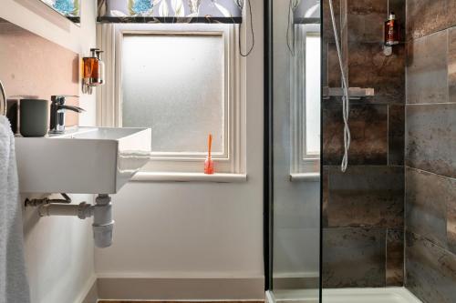 uma casa de banho com um lavatório e um chuveiro em Finest Retreats - Sunnycroft Penthouse em Llandrindod Wells