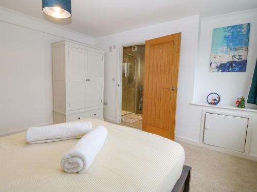 a bedroom with a white bed with a towel on it at Machlud Haul in Llwyngwril