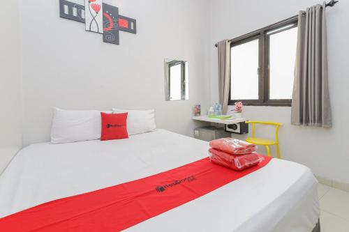 RedDoorz Plus At K23 Rungkut Madya في سورابايا: غرفة نوم مع سرير مع بطانية حمراء عليه