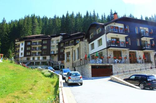 a large building with cars parked in a parking lot at Спа,ски апартамент Дайли, Стрийм Ризорт Пампорово in Pamporovo