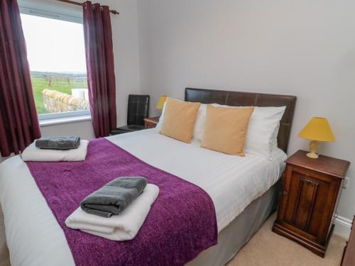 a bedroom with a large bed with towels on it at High Barns Cottage in Morpeth