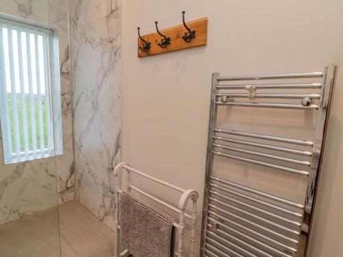 a bathroom with a metal towel rack next to a shower at High Barns Cottage in Morpeth