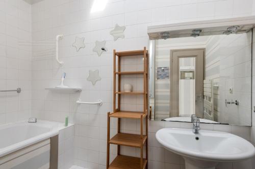 La salle de bains blanche est pourvue d'un lavabo et d'un miroir. dans l'établissement Appartement Neptune, à Saint-Martin-de-Ré