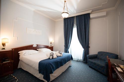コントゥルシにあるHotel Terme Rosapepeのベッドと椅子付きのホテルルーム
