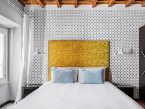 a bedroom with a white bed with a yellow headboard at numa I Vici Rooms & Apartments in Rome