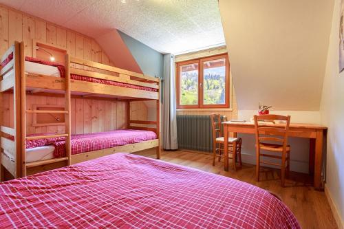 - une chambre avec des lits superposés, un bureau et une table dans l'établissement GITE AUBERGE L'HERBE TENDRE, à Saint-Pierre-dʼEntremont