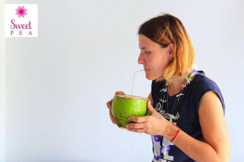 a woman drinking from a green apple with a straw at Sweet Pea Homestay in Balapitiya