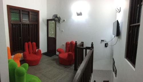 uma sala de estar com cadeiras vermelhas e uma televisão em Sweet Pea Homestay em Balapitiya