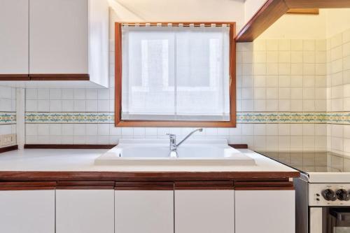 a white kitchen with a sink and a window at San Marco Bell Tower House in Venice
