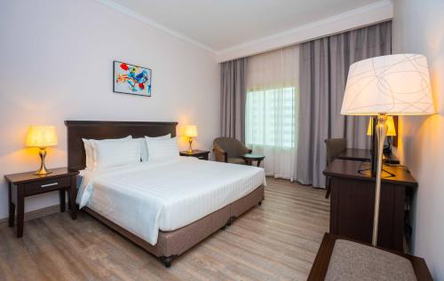 una camera d'albergo con letto, scrivania e lampada di Ezdan Hotel, Residences a Doha