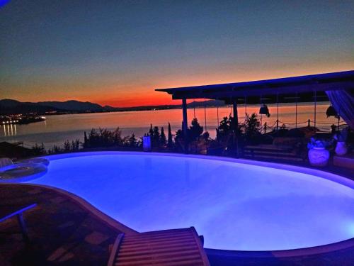 a large swimming pool with a sunset in the background at Magical view, Villa Asproneri, Kamena Vourla in Kamena Vourla