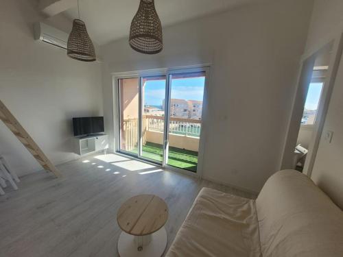 un soggiorno con tavolo e una grande finestra di Béréa - Les Cormorans - Vue port et mer a Frontignan