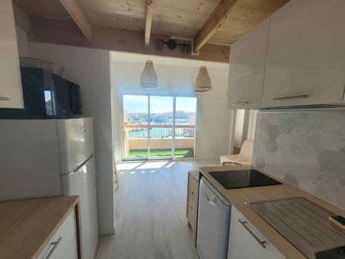 una cucina con elettrodomestici bianchi e una grande finestra di Béréa - Les Cormorans - Vue port et mer a Frontignan
