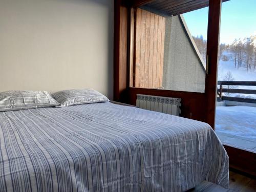 a bedroom with a bed and a large window at Cervinia Ski In Ski Out - Family Studio in Breuil-Cervinia