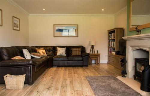 a living room with a leather couch and a fireplace at Strath Glebe in Kilbride