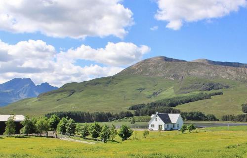 a white house in a field with mountains in the background at Strath Glebe in Kilbride