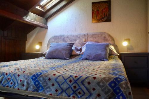 a bedroom with a bed with blue pillows at La Casa Suites Albaredo di Rotzo 