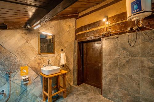 a bathroom with a sink and a wooden door at Zostel Homes Laida (Jibhi) in Sainj