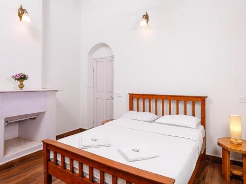 a bedroom with a white bed with a fireplace at DEVASHOLA HOMESTAY in Coonoor