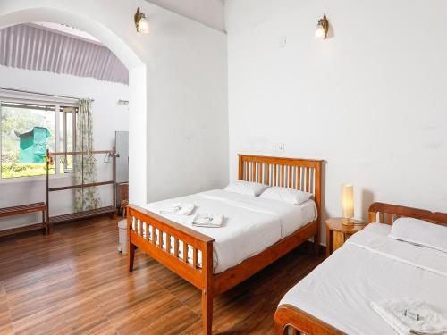 a bedroom with two beds and a window at DEVASHOLA HOMESTAY in Coonoor