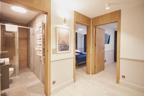 a bathroom with a walk in shower next to a bedroom at Timber Apartments by Baltic Home in Świnoujście